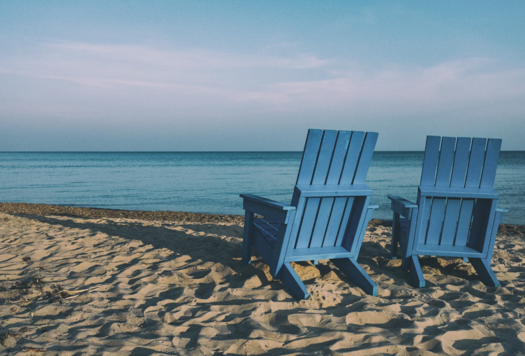two blue wooden chairs on a beach